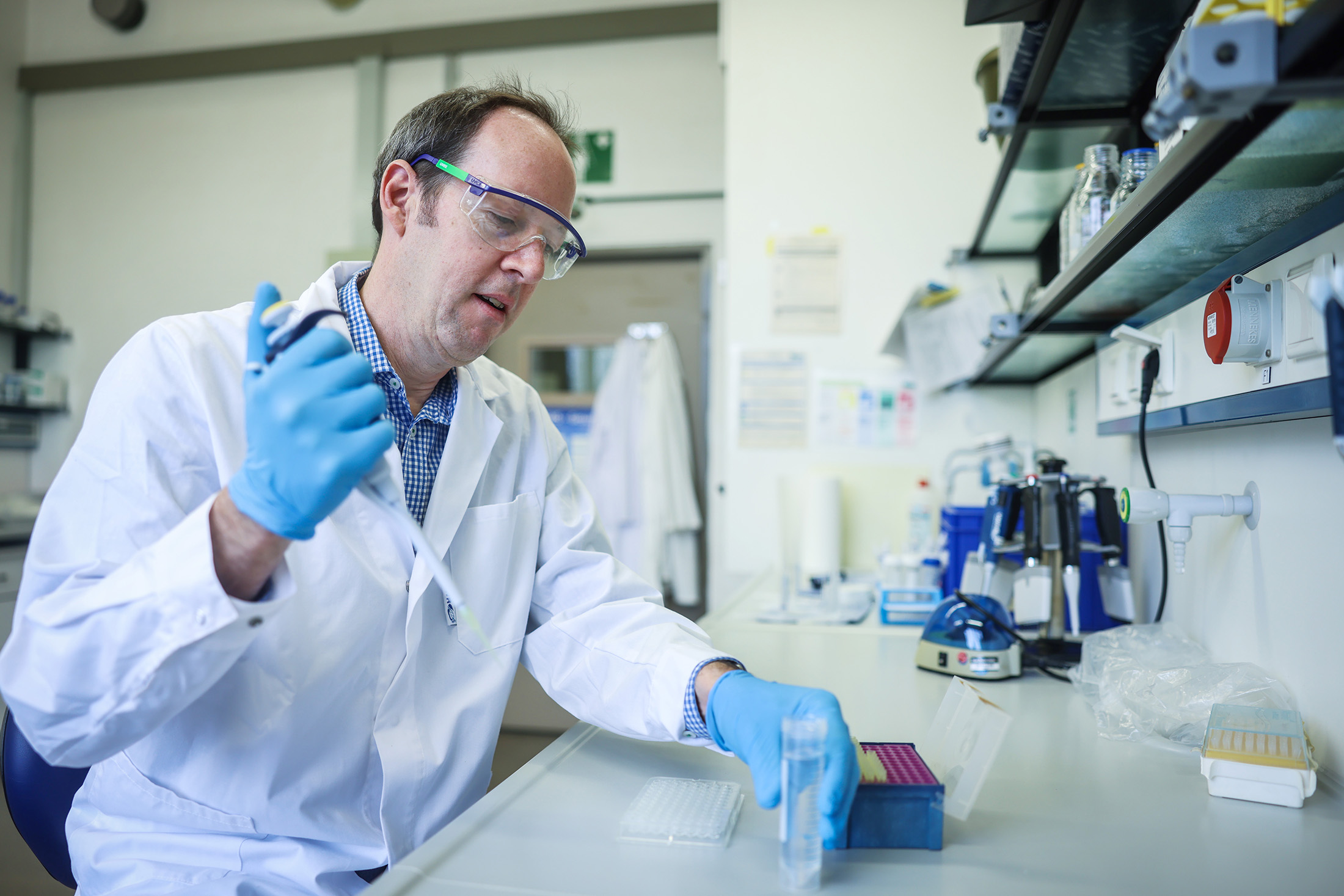 Professor Hoffman, dressed in a lab coat and holding a pipette, works in a laboratory.