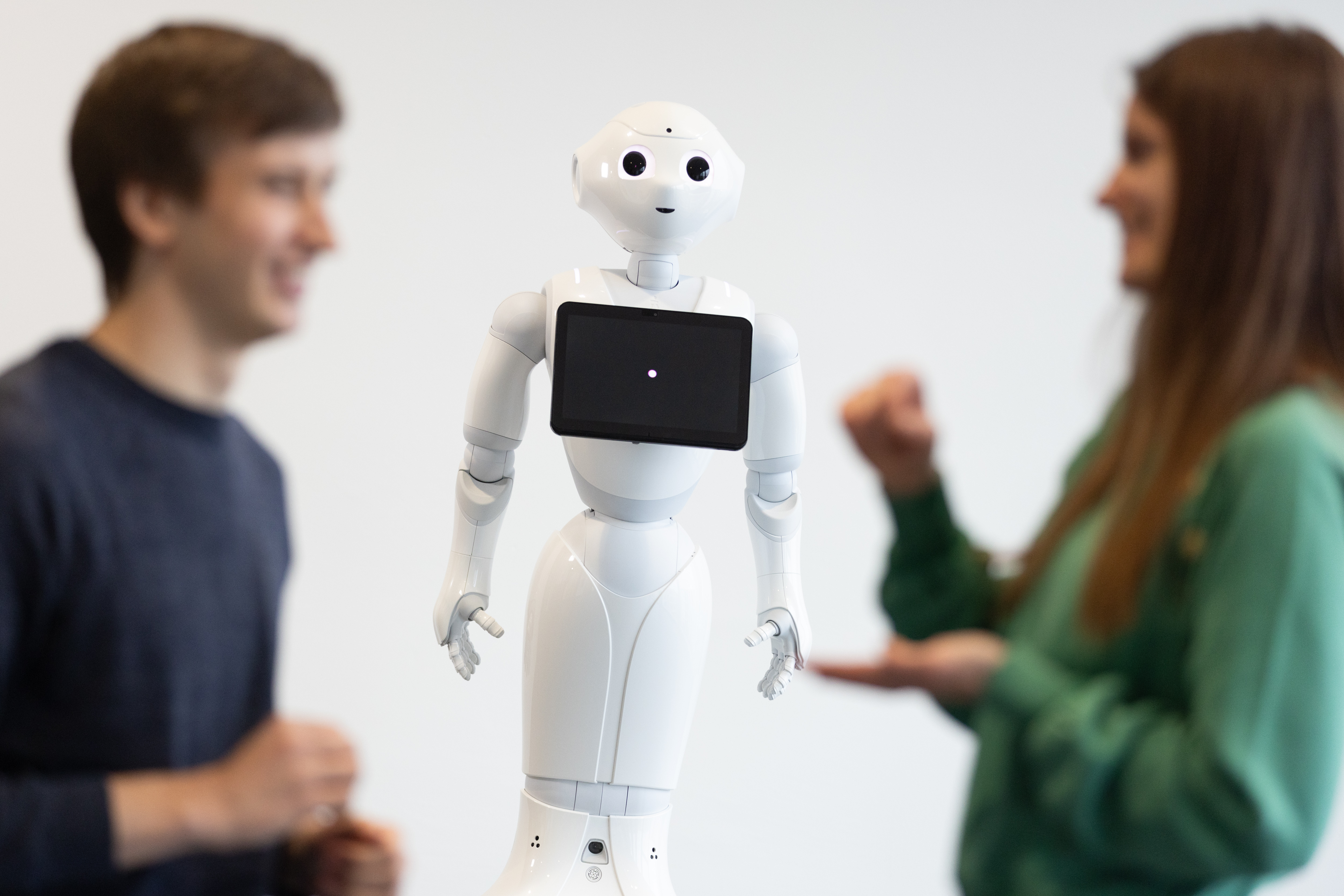People in a conversation in front of a robot.