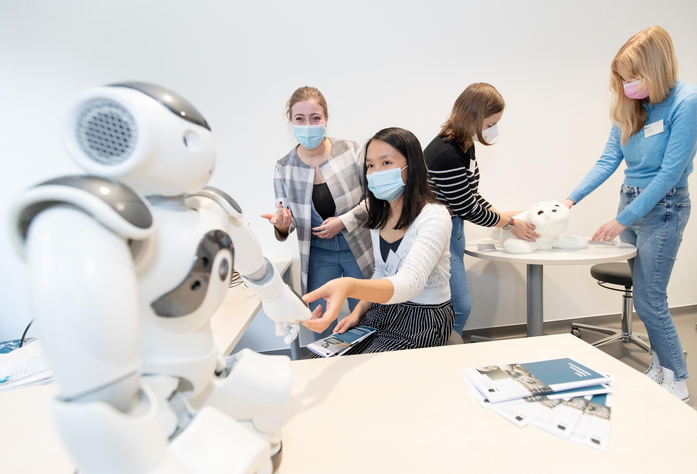 Roboter NAO mit einigen diskutierenden Menschen
