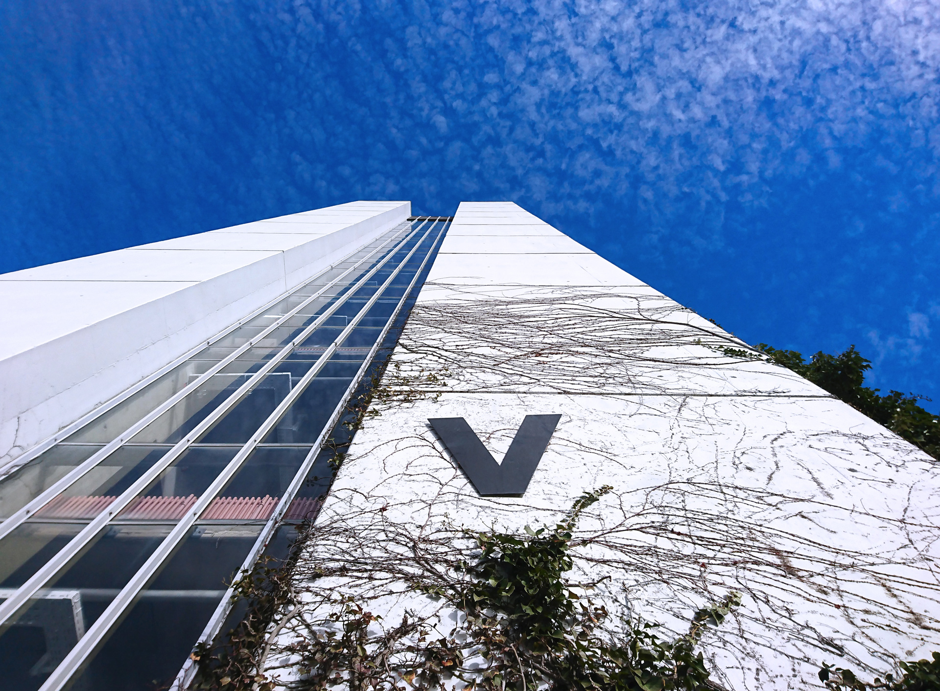 Exterior view of building part V against blue sky with clouds.