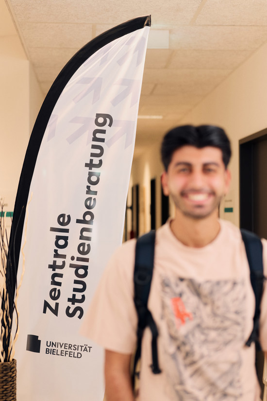 Student vor Fahne "Zentrale Studienberatung"