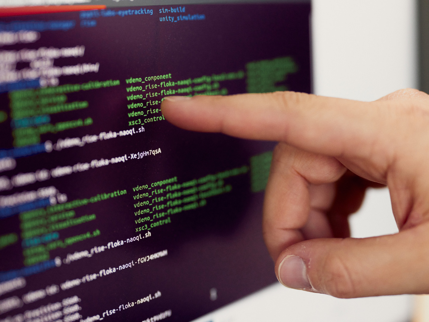 jemand zeigt auf einen Bildschirm auf dem Code zu sehen ist