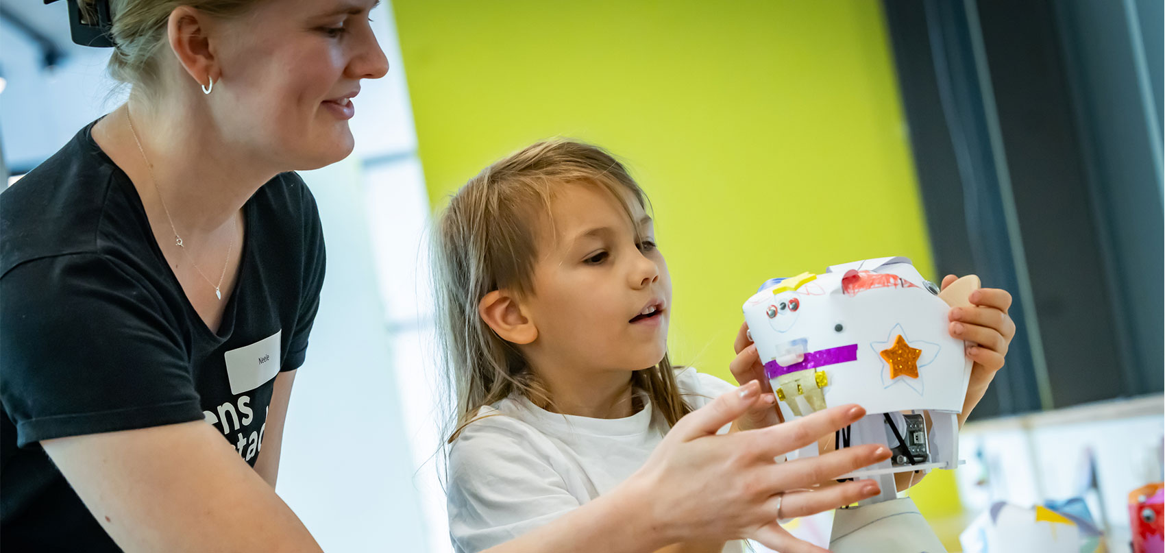 Ein Roboter und ein Mensch bauen zusammen ein Türmchen aus Kugeln.