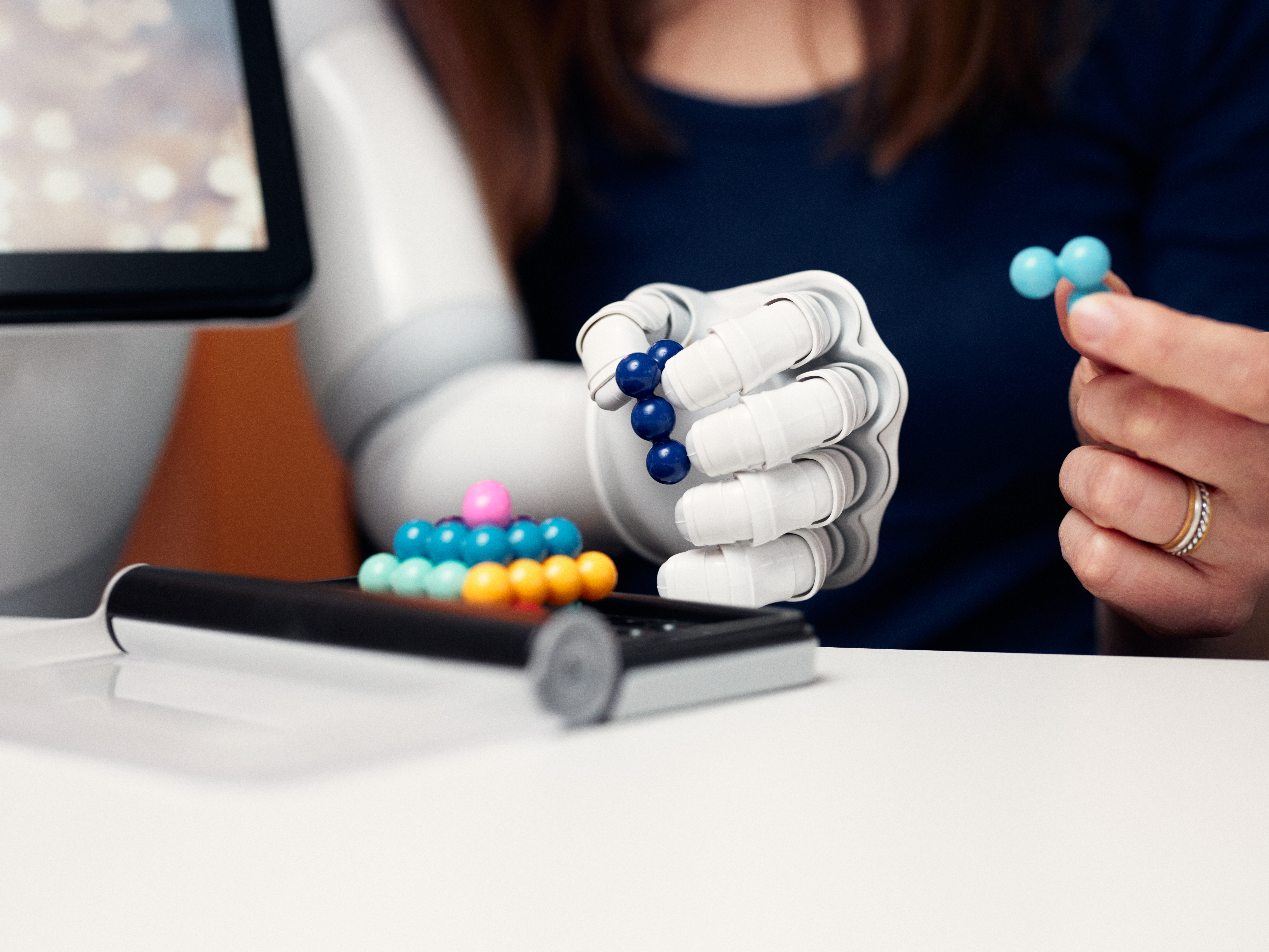 Ein Roboter und ein Mensch bauen zusammen ein Türmchen aus Kugeln.