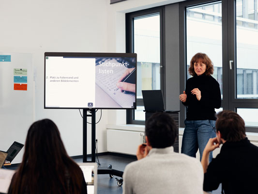 Eine Gruppe Menschen steht vor einem Whiteboard und diskutiert über die Ergebnisse an dem Whitboard