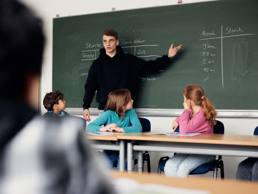 Lehrer an Tafel vor Klasse