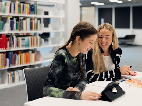 Zwei Frauen lernen gemeinsam an einem Tablet in der Bibliothek