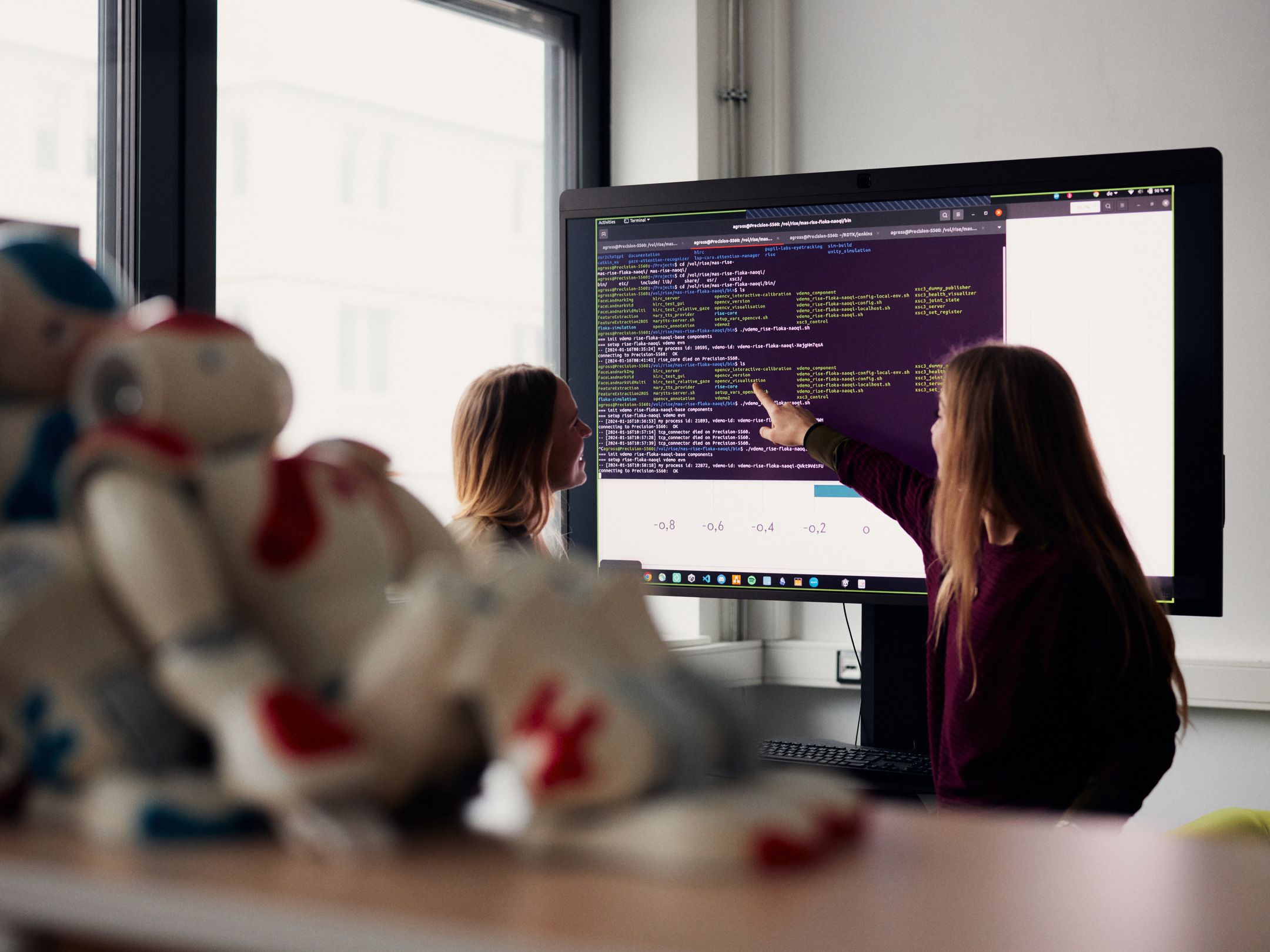 Woman stands in front of virtual robot head Flobi