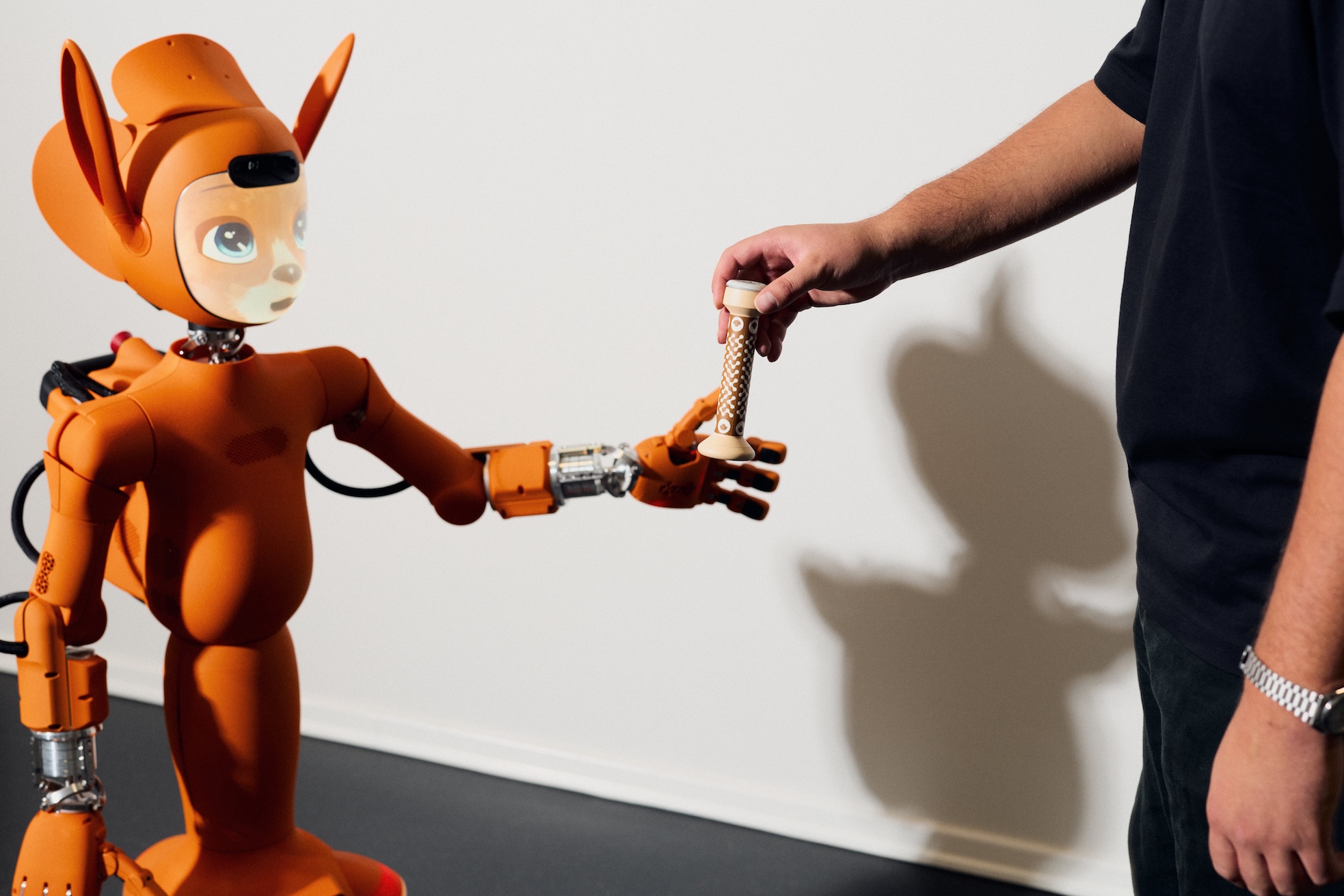 Ein Forschender reicht Miroka einen Lerngegenstand