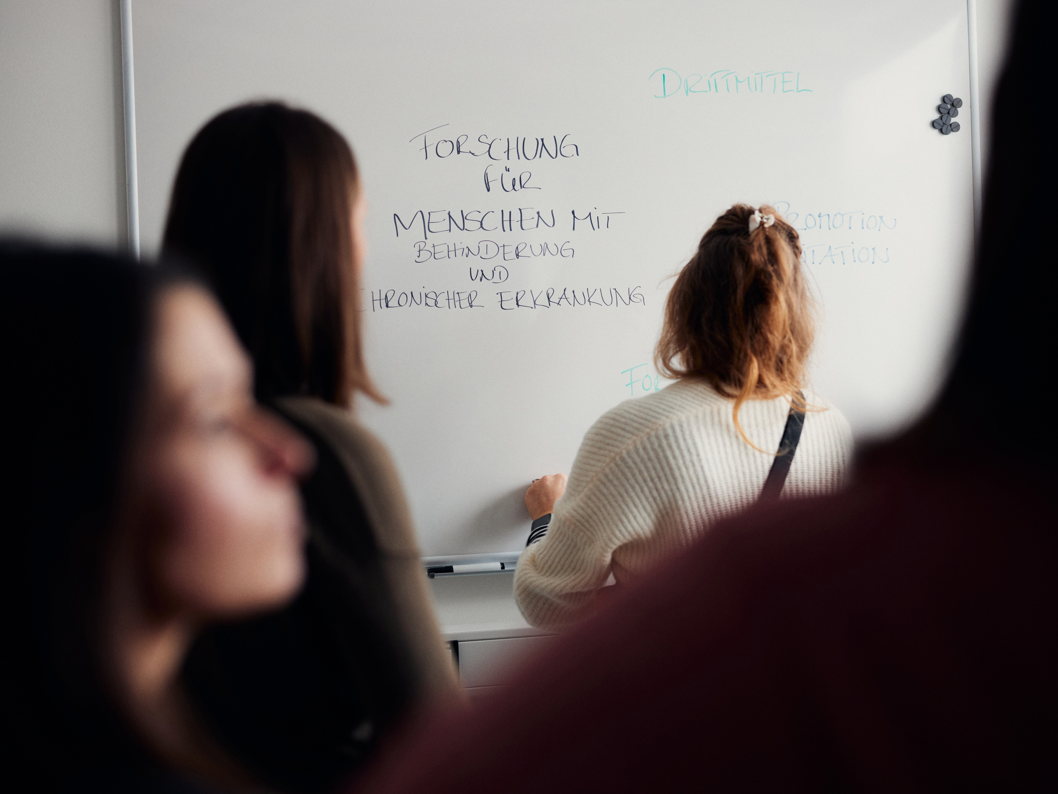 Woman stands in front of virtual robot head Flobi