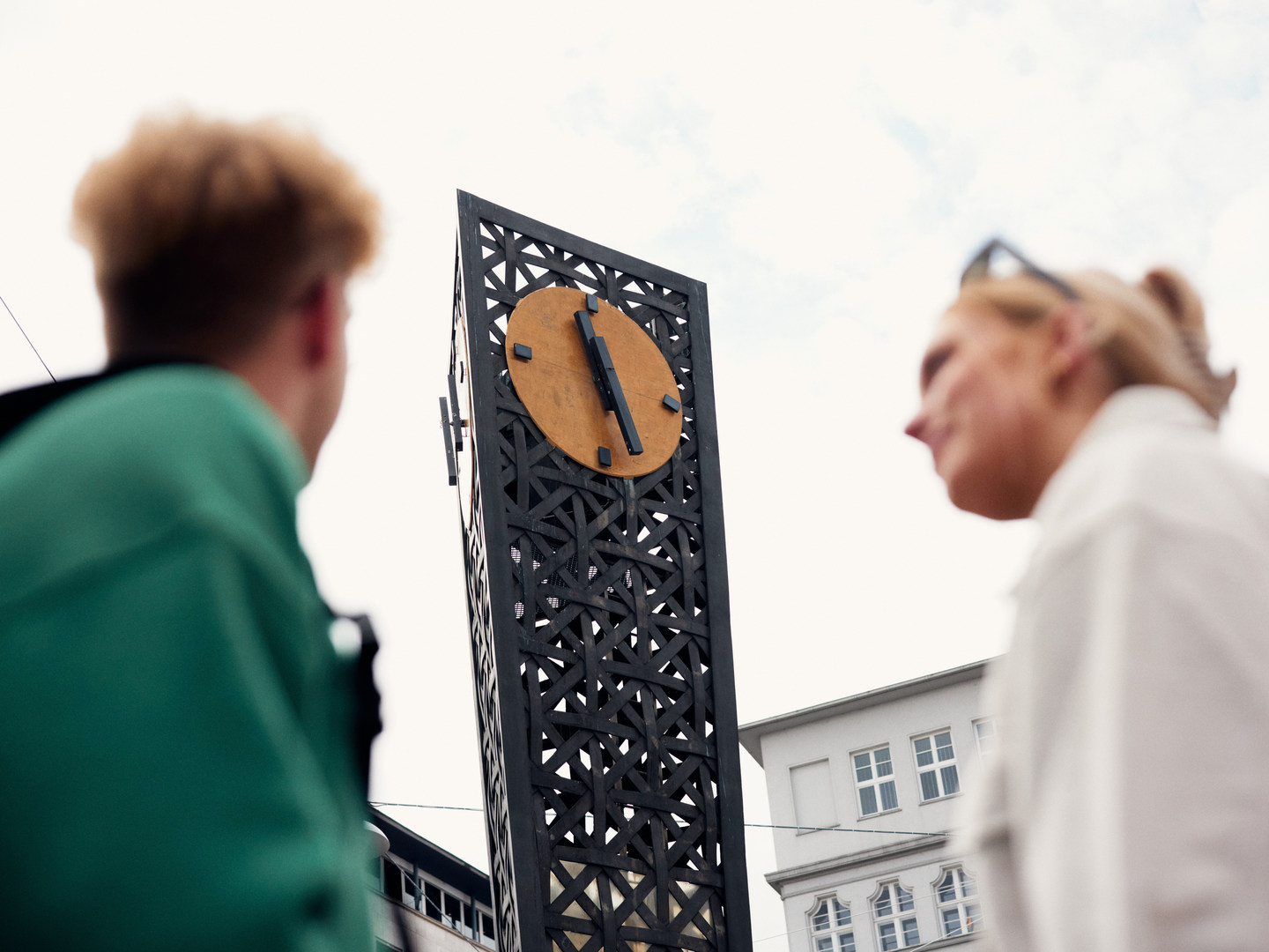 Zwei Personen blicken hoch zur Uhr am Jahnplatz