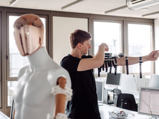 Man stands next to robot and straps equipment around his arm