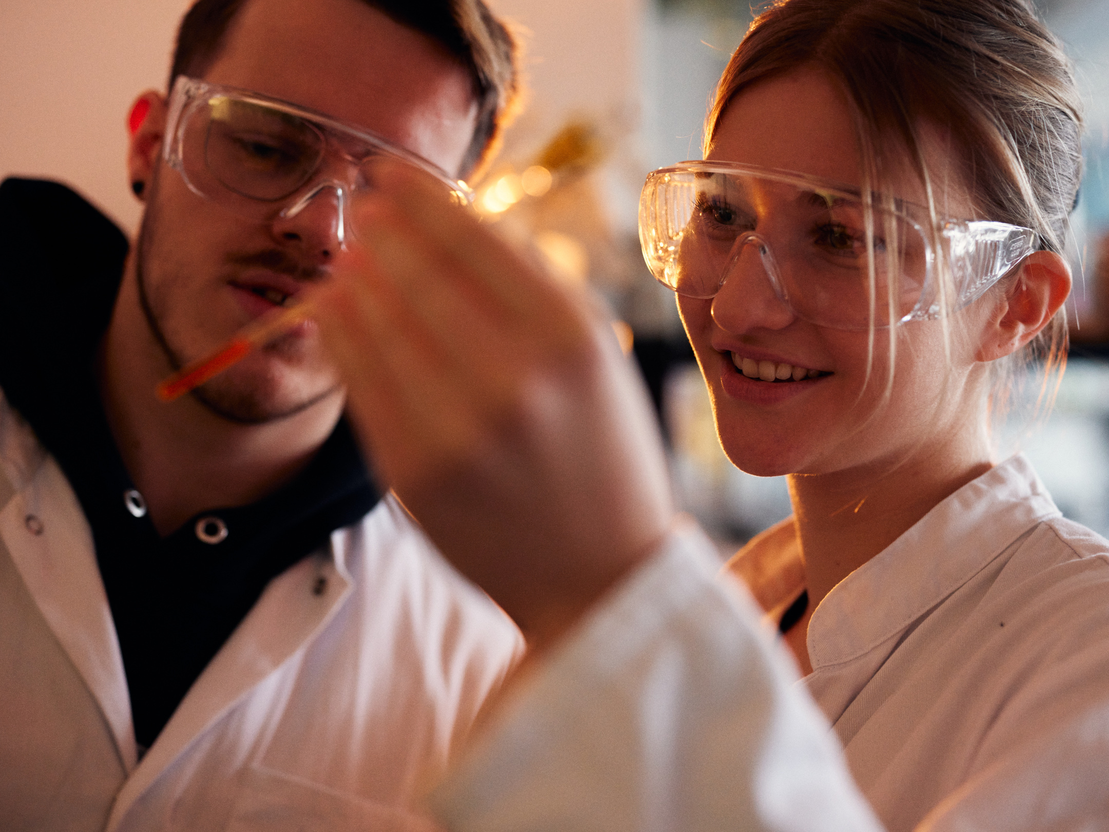 Eine Chemiestudentin und ein Chemiestudent schauen eine Pipette an.