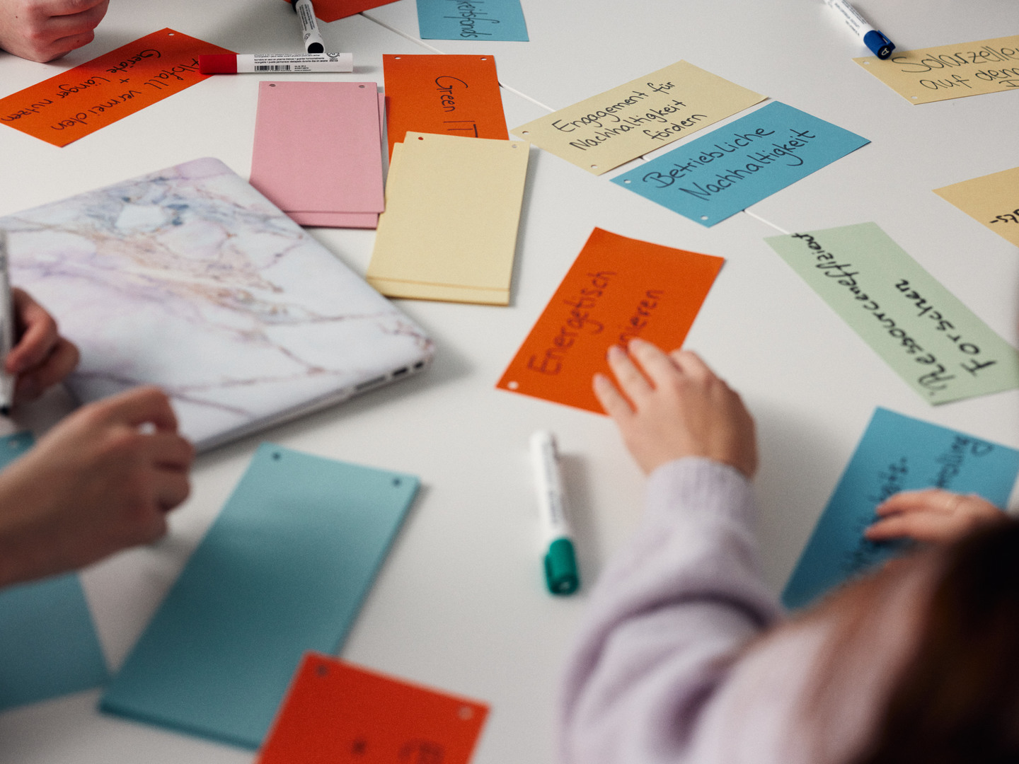 Studierende legen Kärtchen auf einen Tisch
