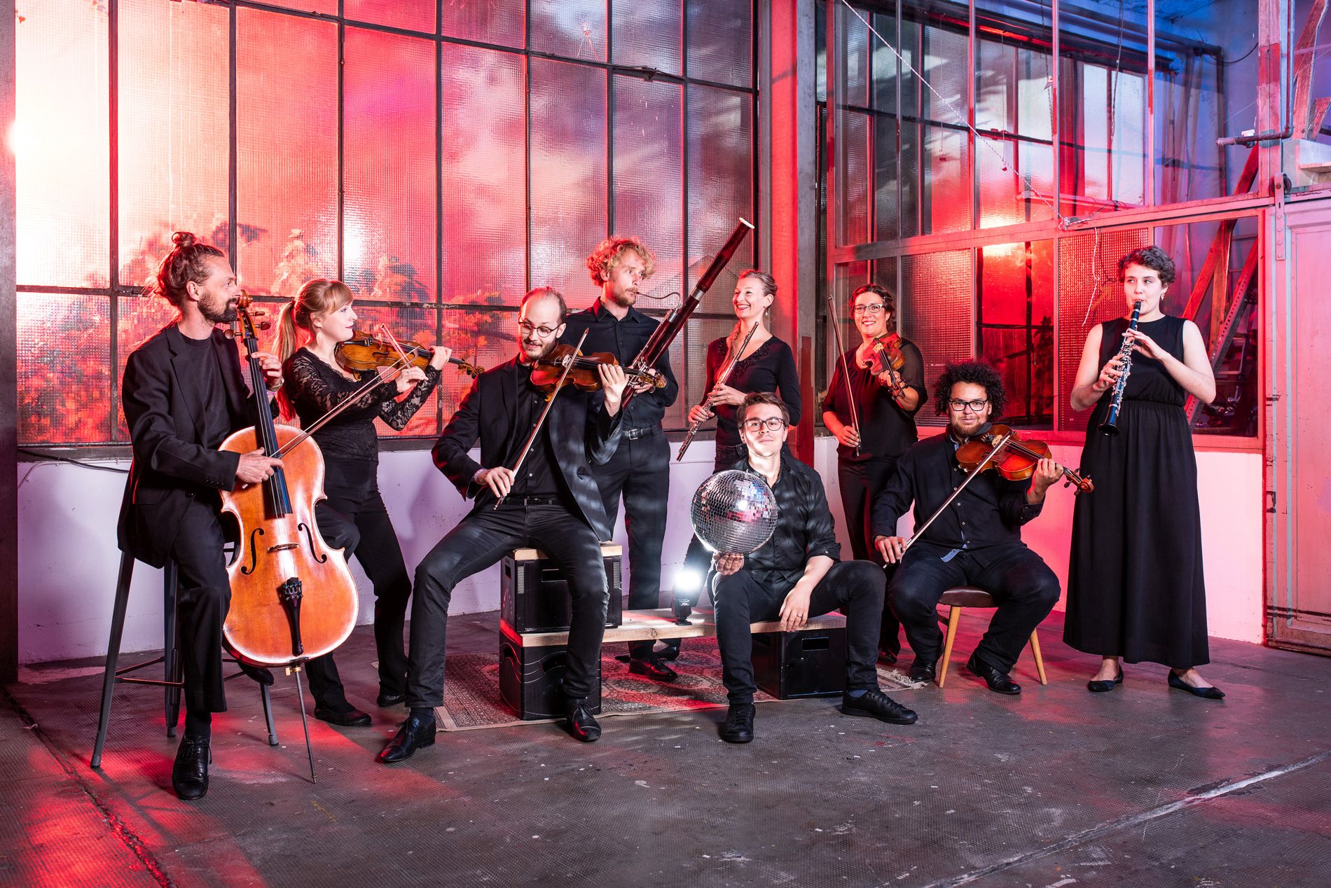 Orchestermitglieder mit Instrumenten und einer Disco-Kugel