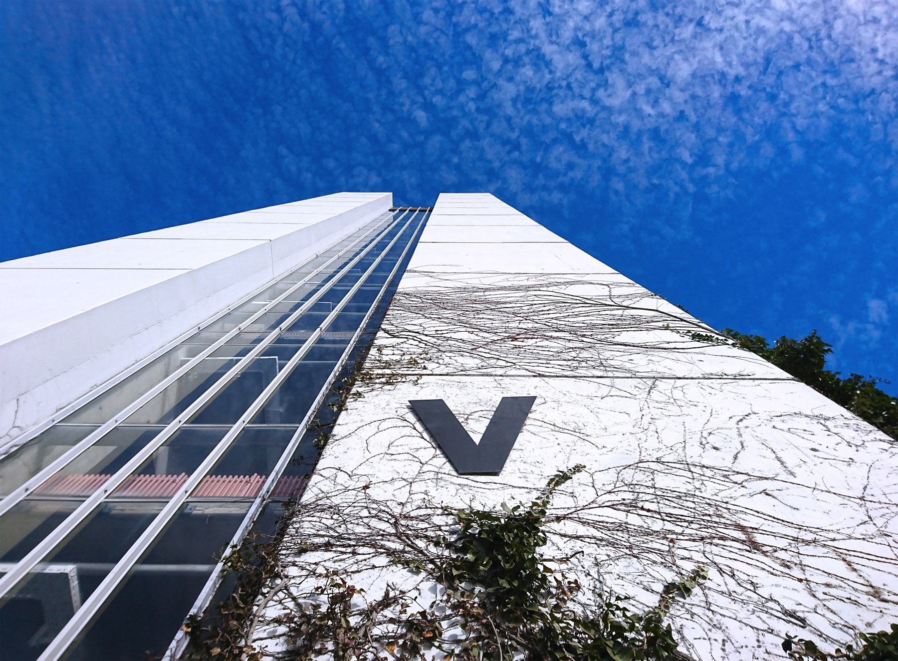 Exterior view of building part V against blue sky with clouds.
