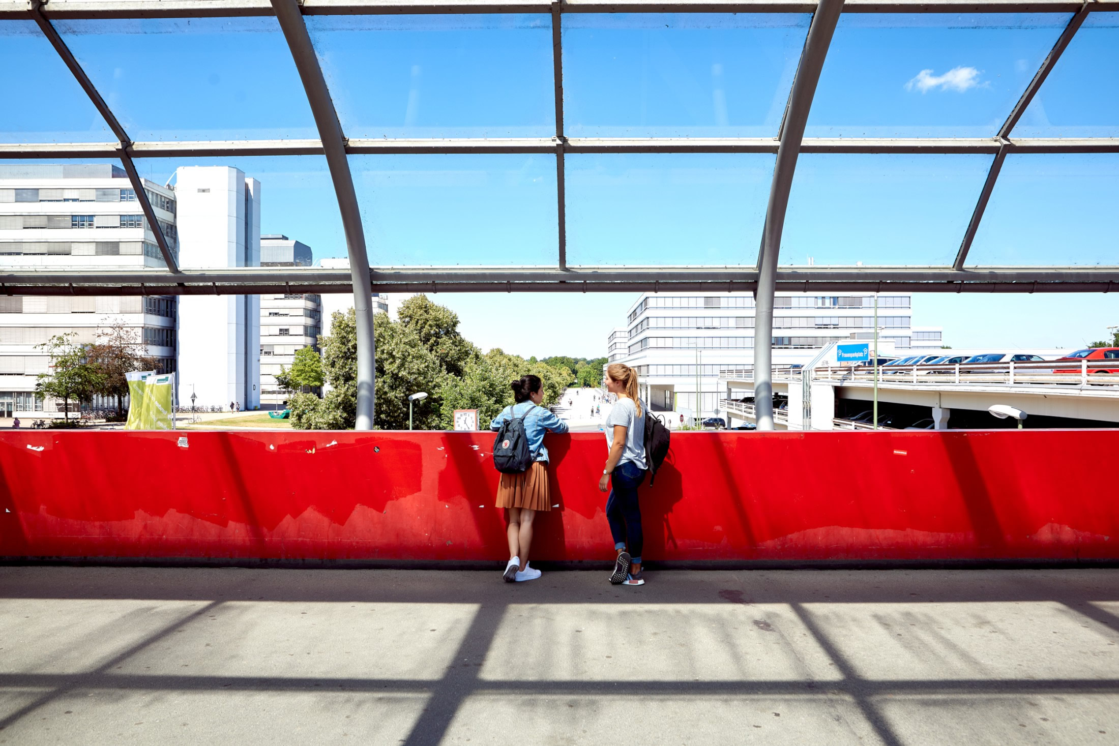 Auf dem Foto ist die rote Brücke zur Universität mit zwei Personen zu sehen.