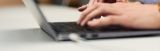Hände, die auf einer Laptoptastatur tippen