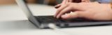 Hands typing on a laptop keyboard