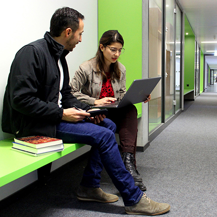 Image with one male and one female student, studying in the hall of the Center for InterAmerican Studies