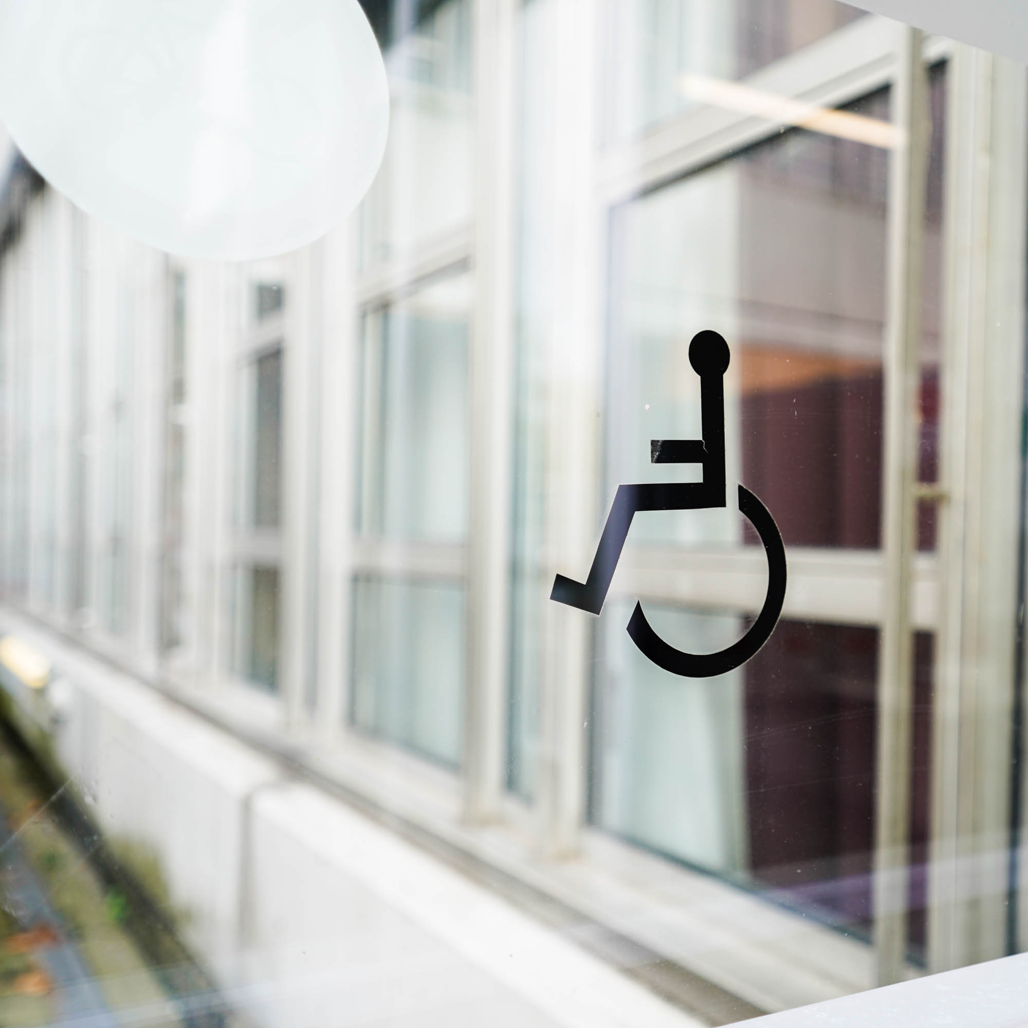 On a glass door the abstract sign of a wheelchair user