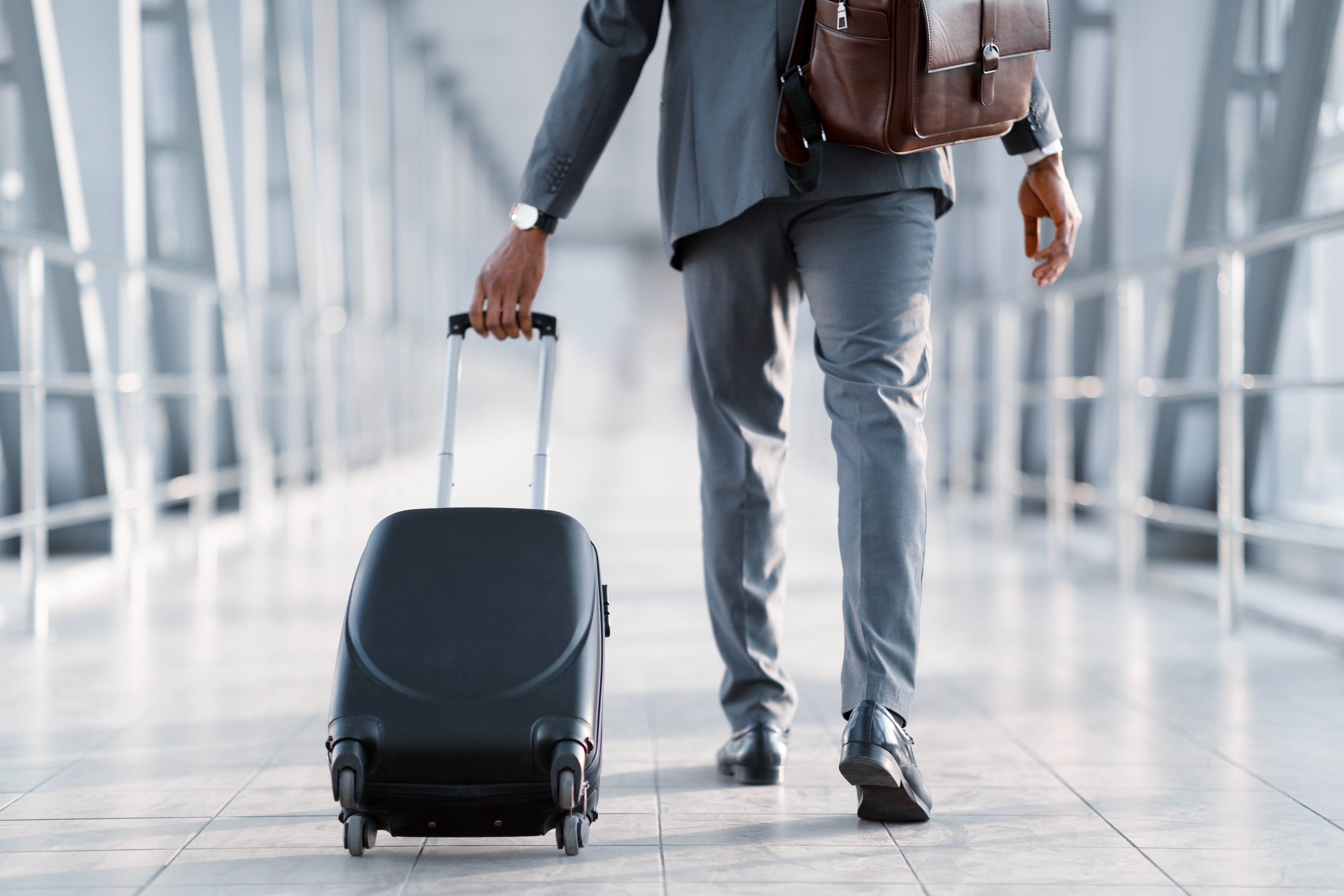 Business trip. Businessman carrying suitcase, back view