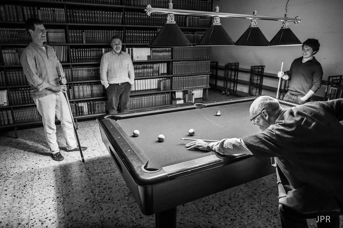 Someone playing pool, leaning over the table, the queue in their hand, black and white photo