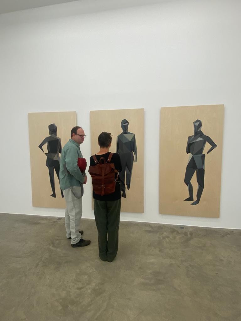 Zwei Personen vor Bildern einer Ausstellung
