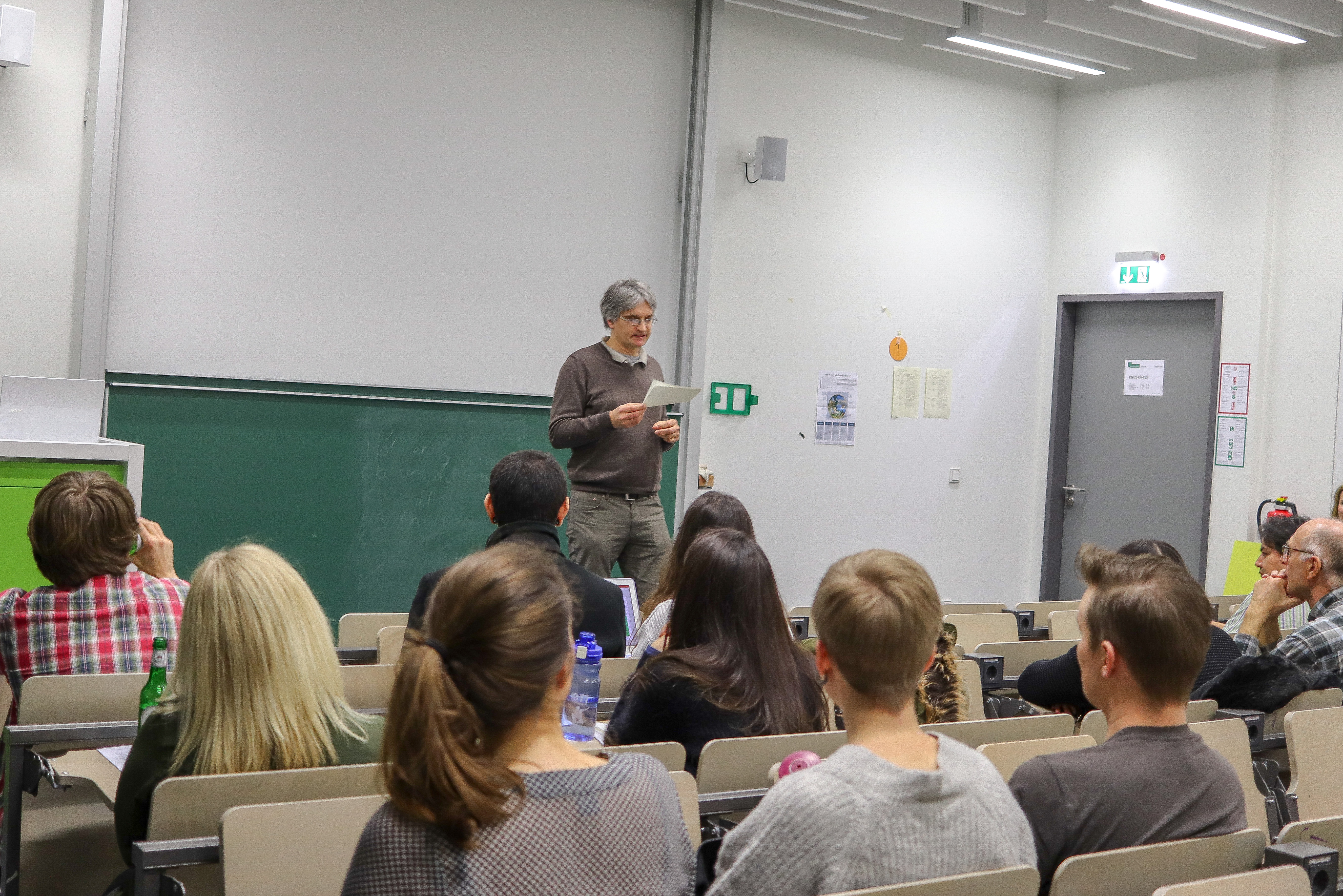 The picture shows professor Michael teaching, standing in front of some students 