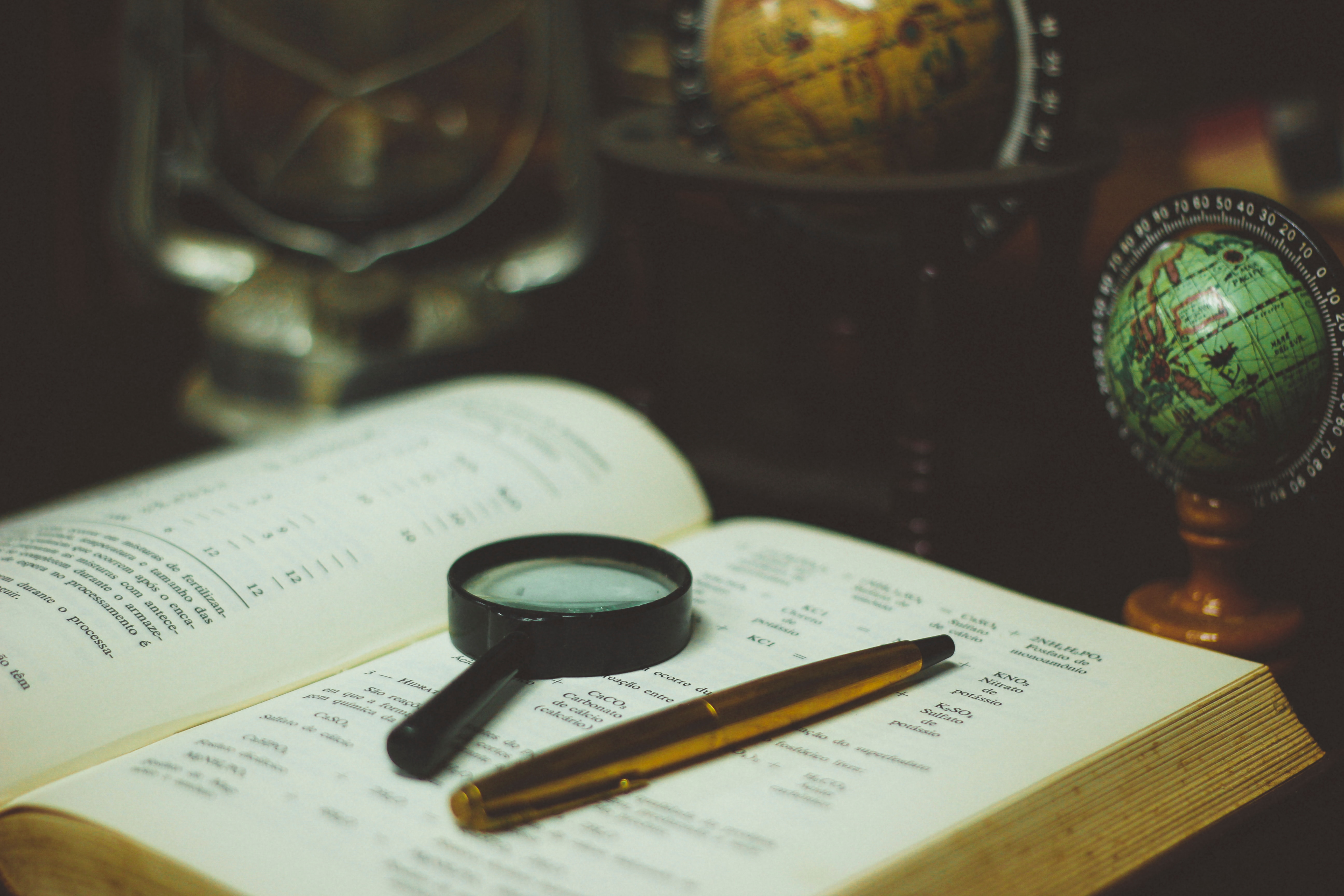 Open book with magnifying glass and pen. 