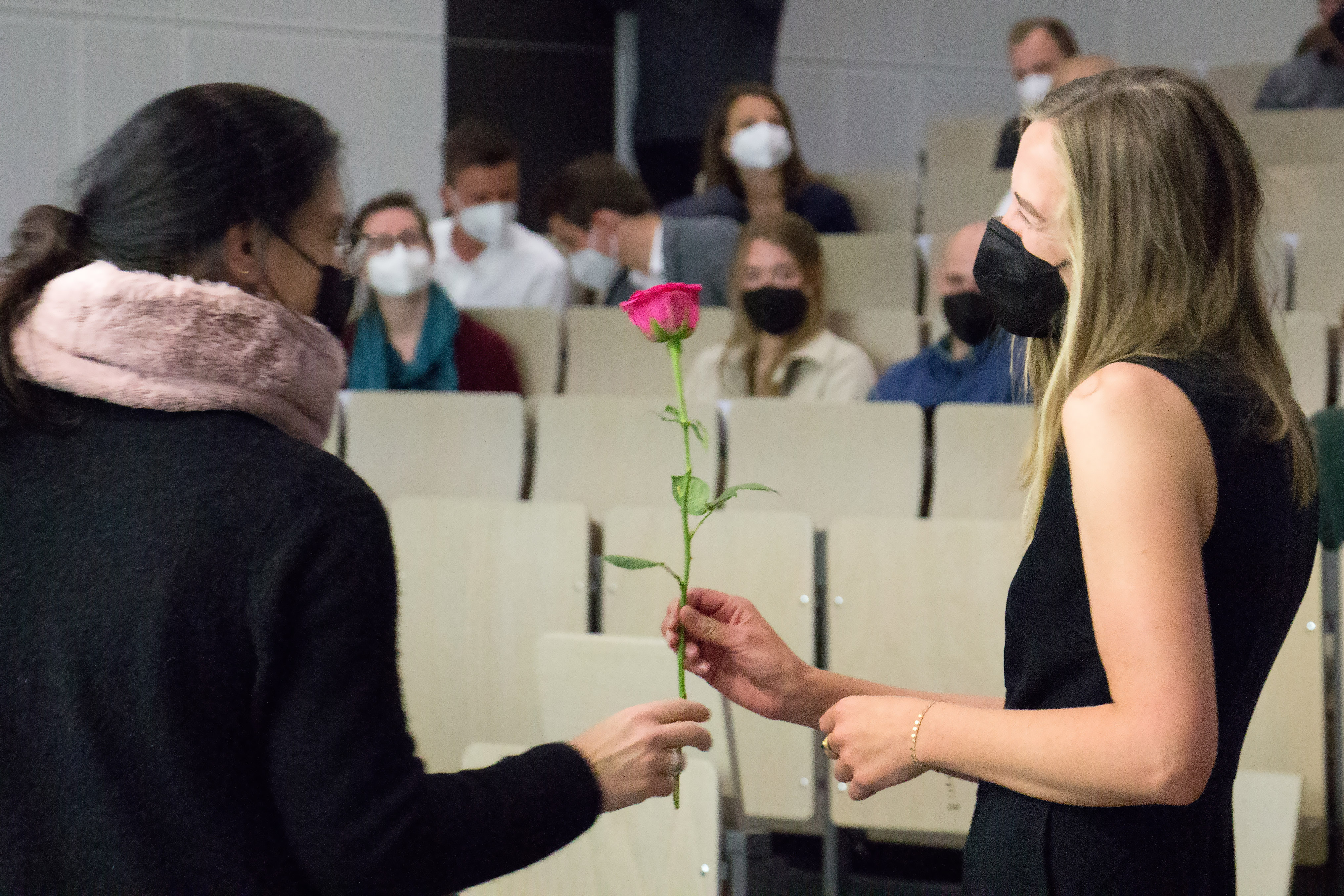 Frau überreicht Absolventin eine Rose