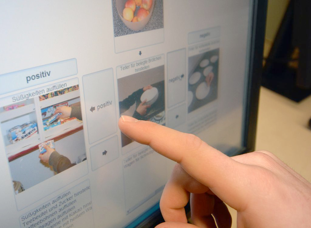 A hand in front of a touch screen with images to choose 