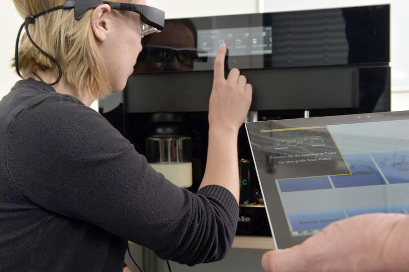 A person with data glasses in front of a coffee machine