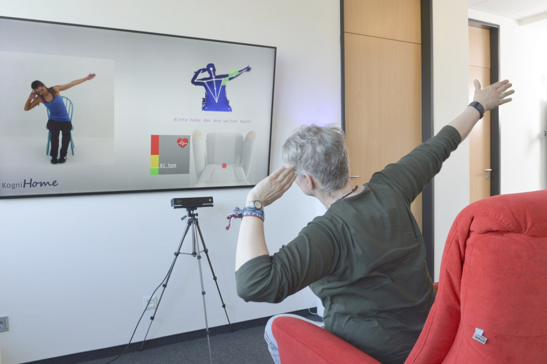 A seated person imitates the movements of an avatar on a screen