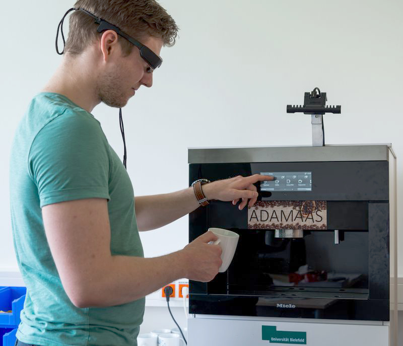 A person with data glasses in front of a coffee machine