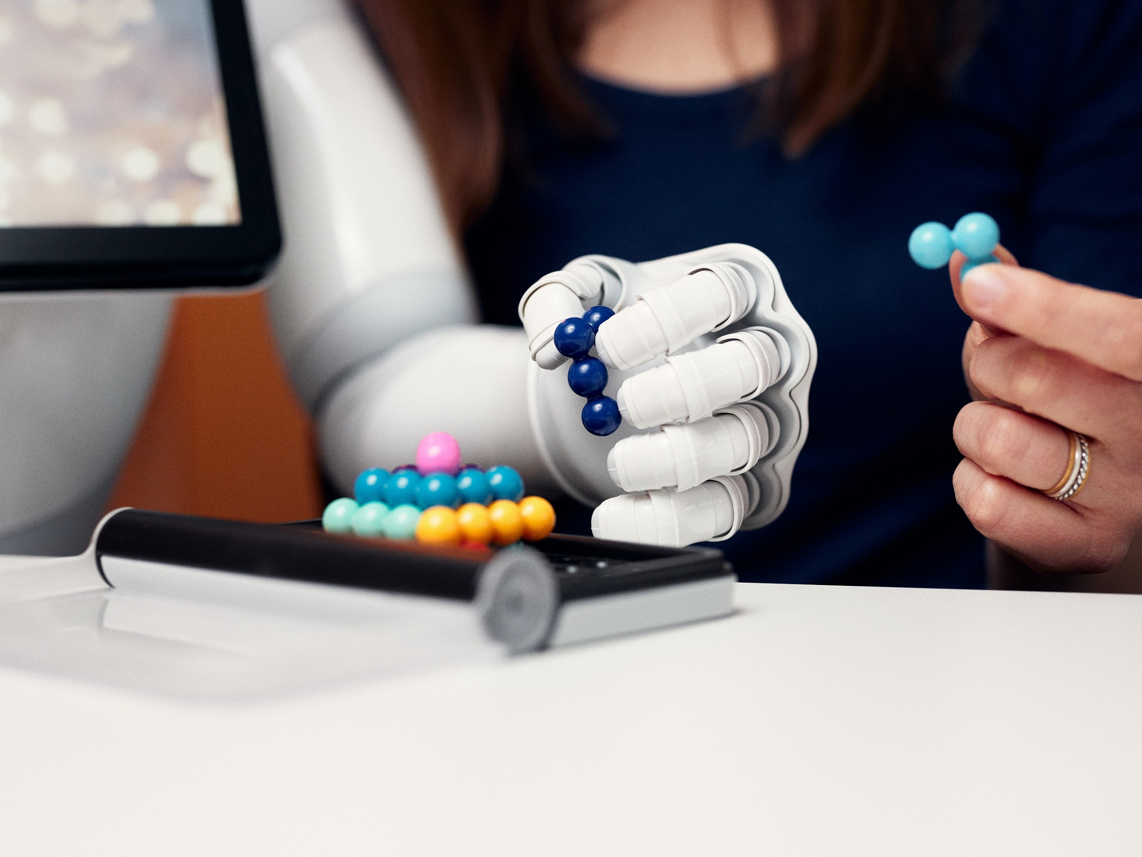 Hands of a robot and a human solving a ball puzzle together