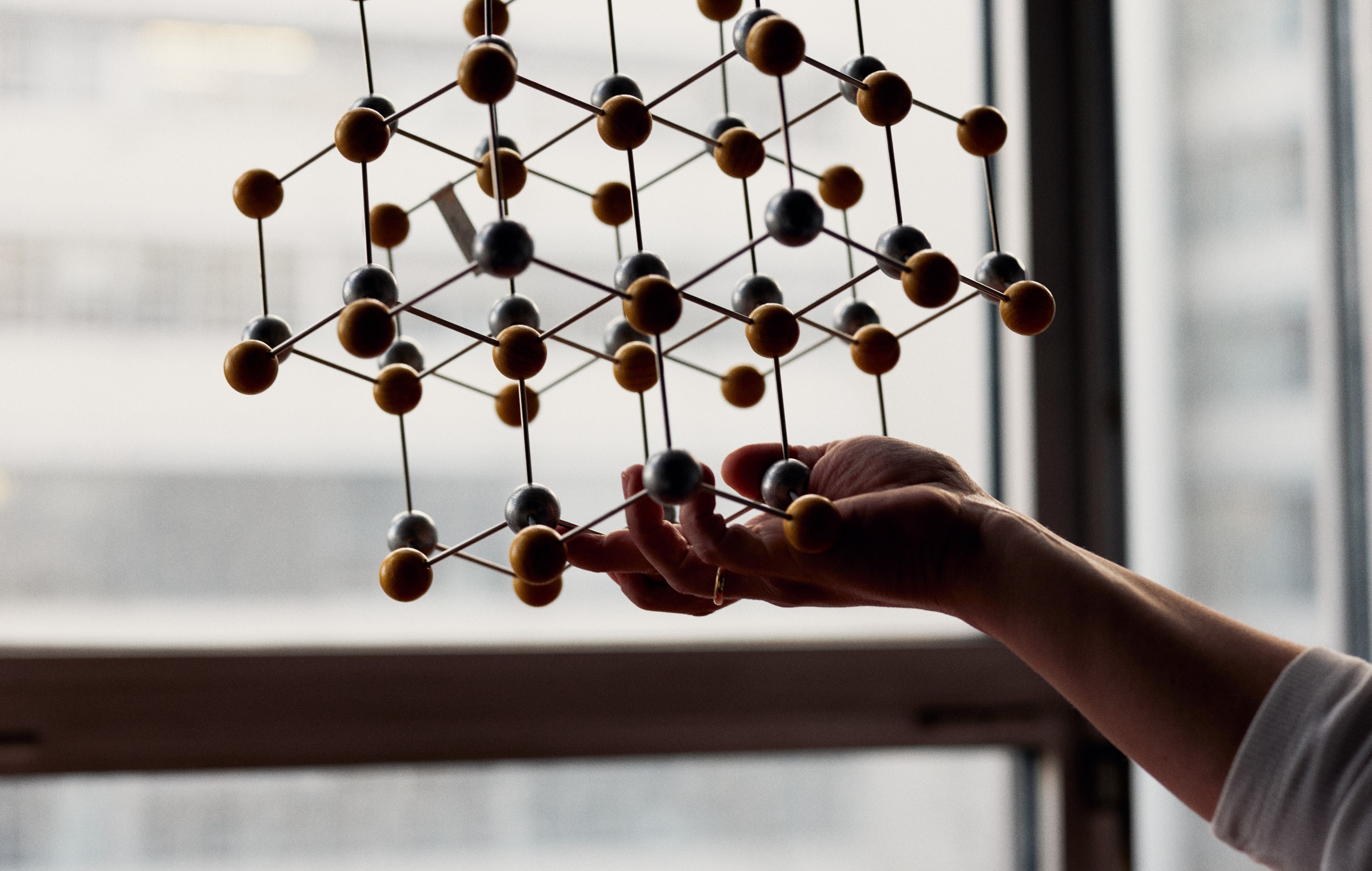 Hand holding large lattice model in front of a window