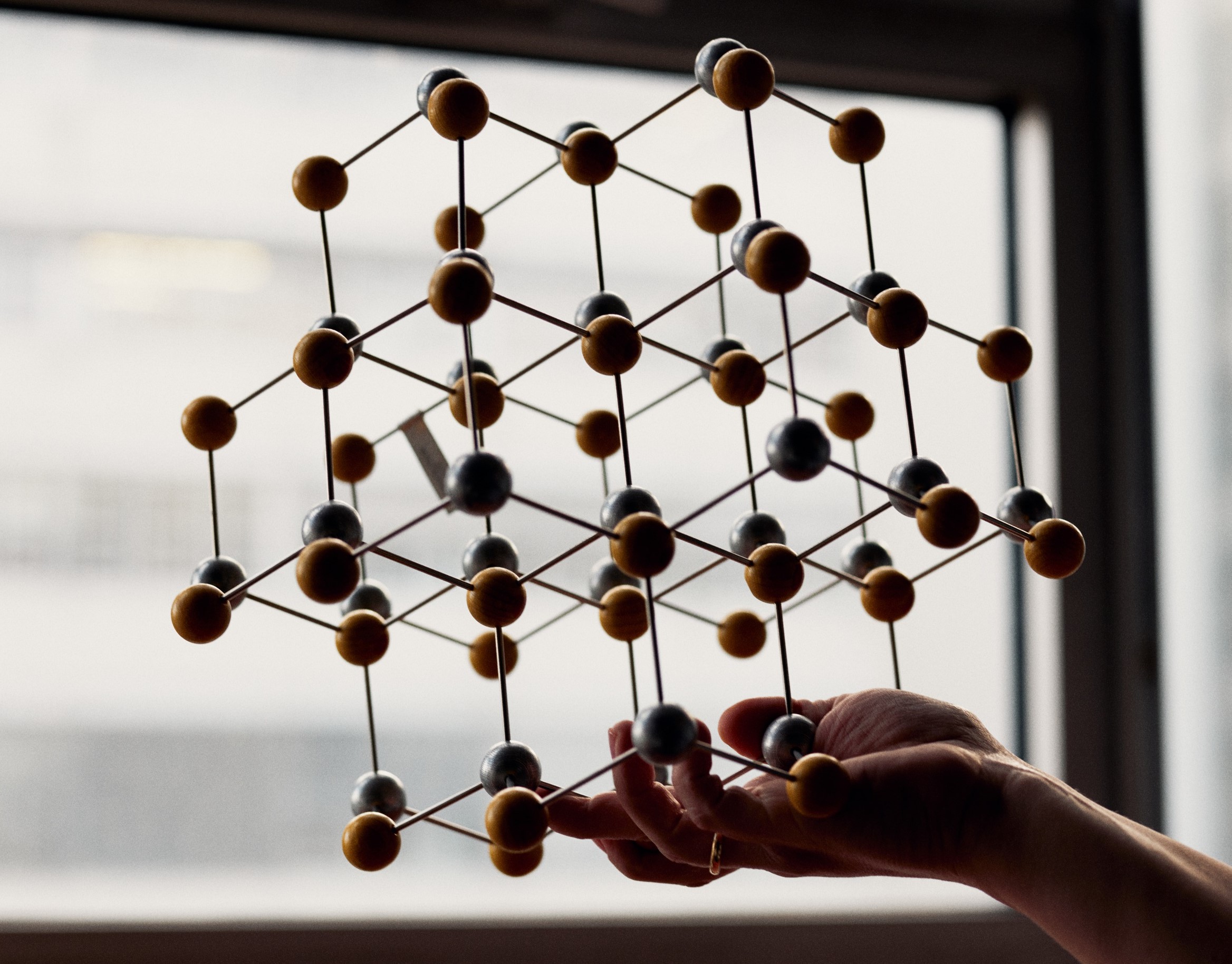Hand holds large grid model in front of a window