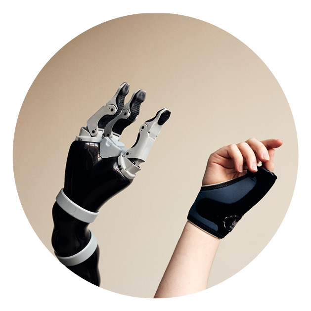 A robot hand is stretched in the air next to a human hand against a sand coloured background