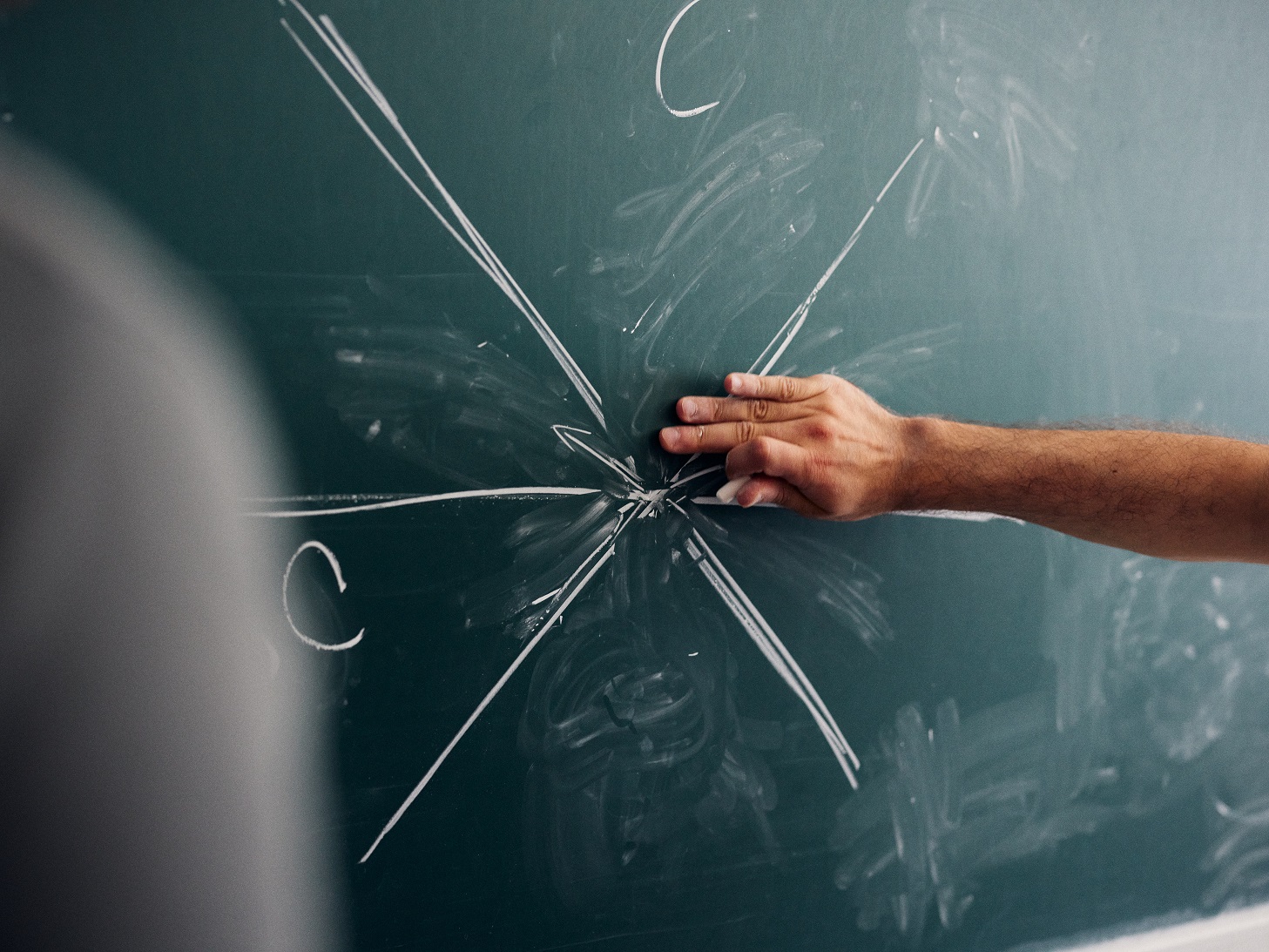 Hand draws mathematical visualisation on a green board