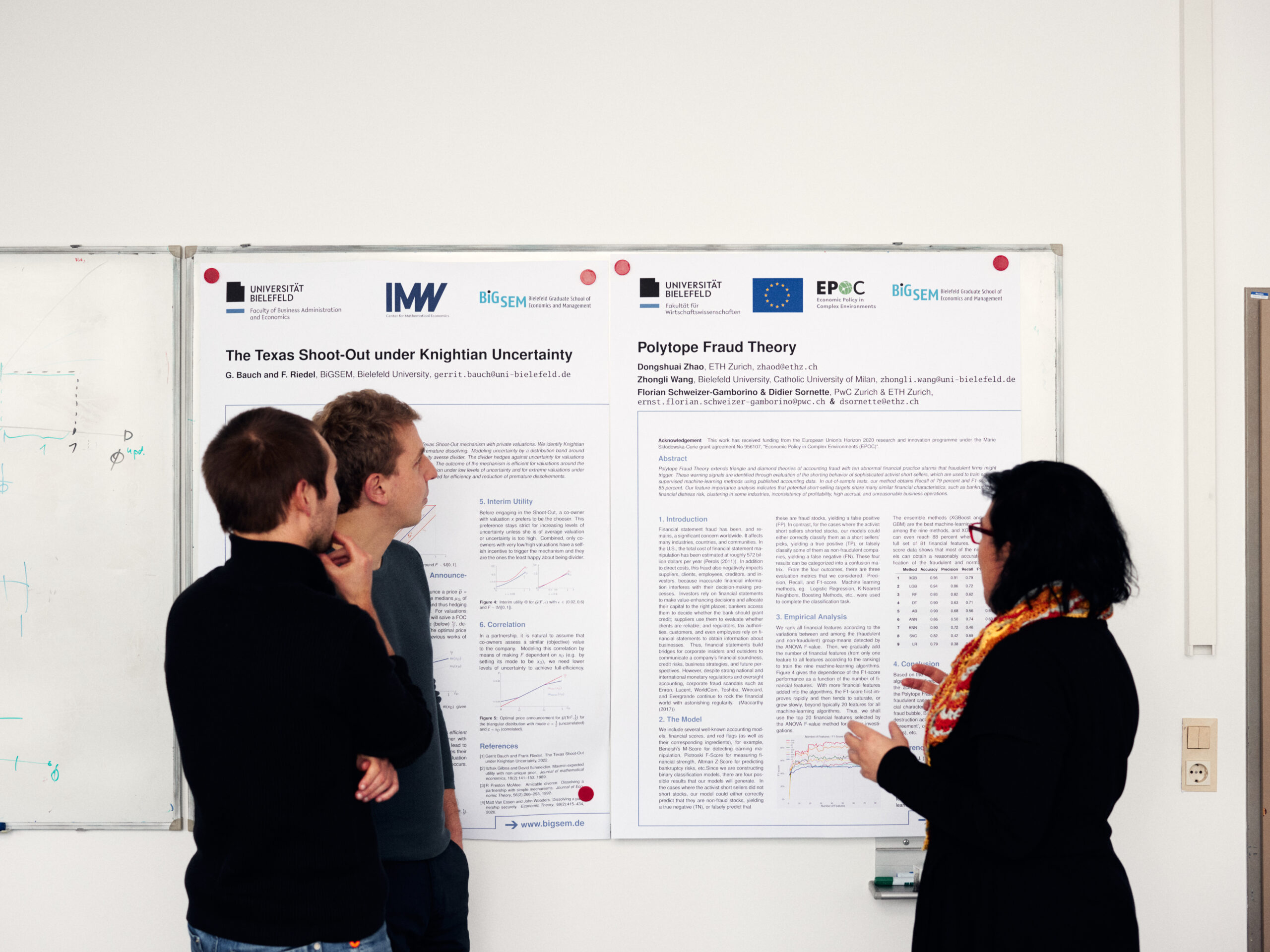 Photo with PhD students discussing next to poster