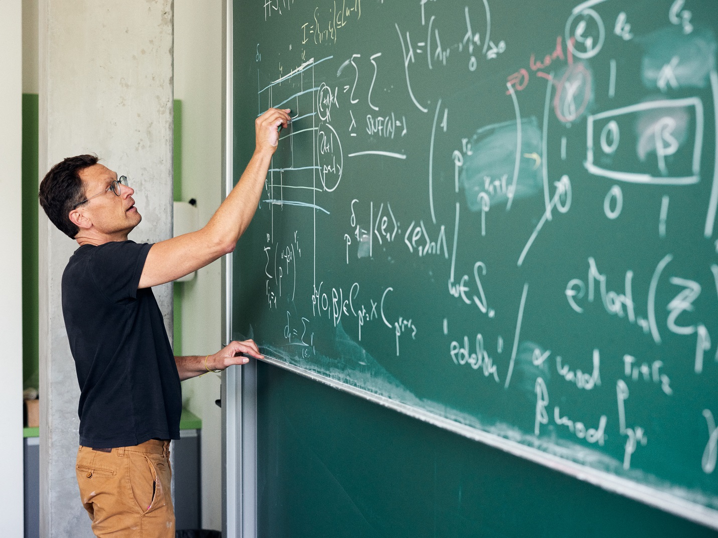 Prof. Dr. Christopher Voll schreibt mathematische Formeln auf eine Kreidetafel