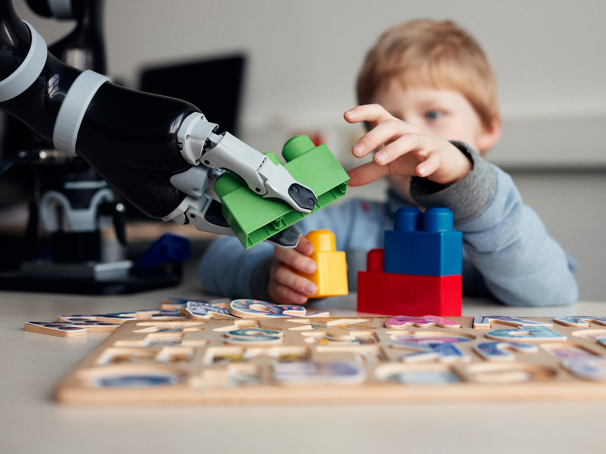 Ein Kind und ein Roboter spielen gemeinsam mit großen Steckbausteinen