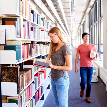 Ein Mann und eine Frau vor einem Bücherregal der Bibliothek