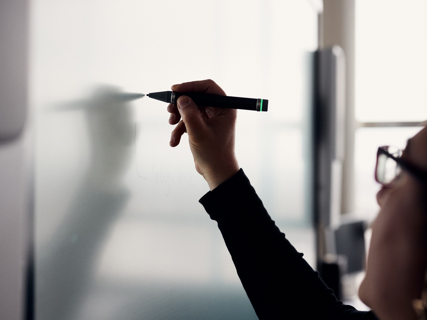 Hand of a person writing with a pen on a white board