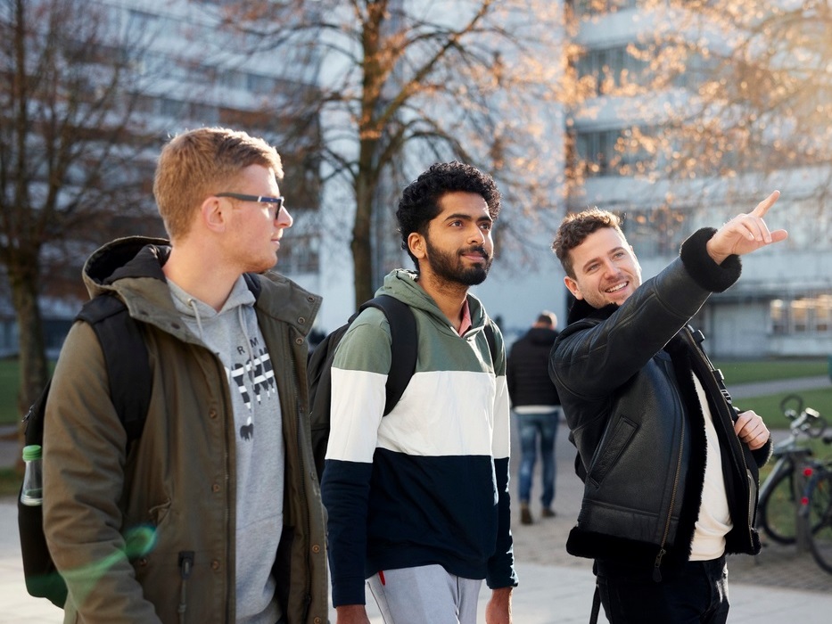 Student zeigt zwei anderen Studenten den Campus