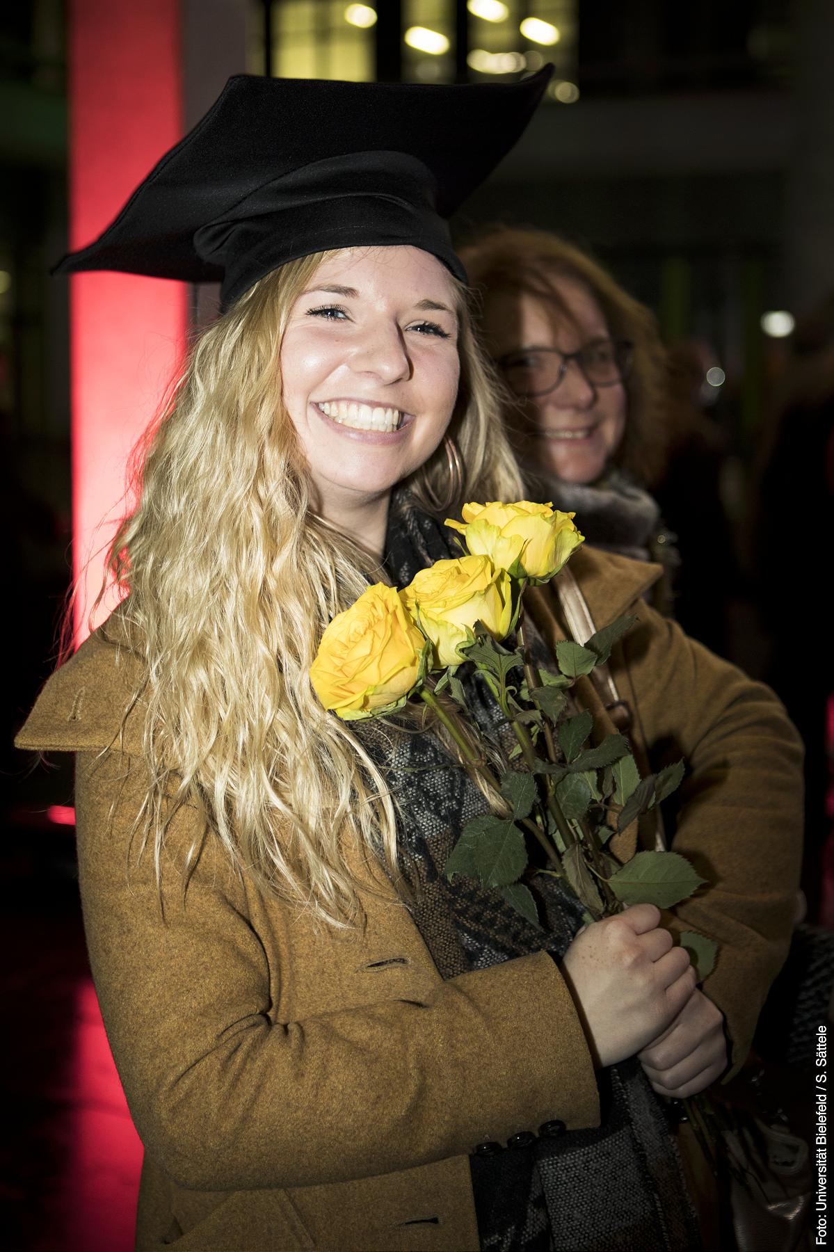 Eine Frau trägt mehrere gelbe Rosen
