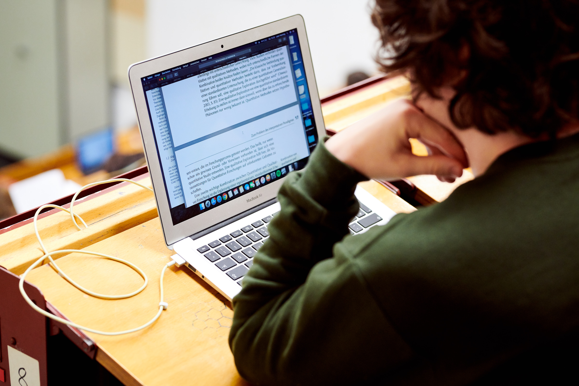 Student sitzt im Hörsaal und schaut auf seinen Laptop