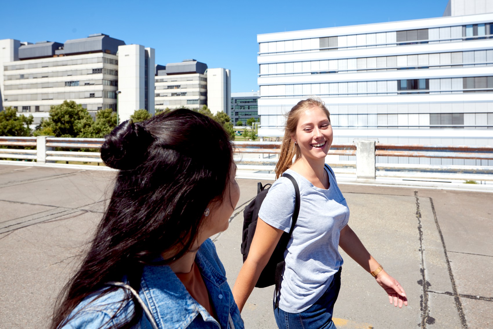 zwei junge Student*innen gehen lächelnd nebeneinander her