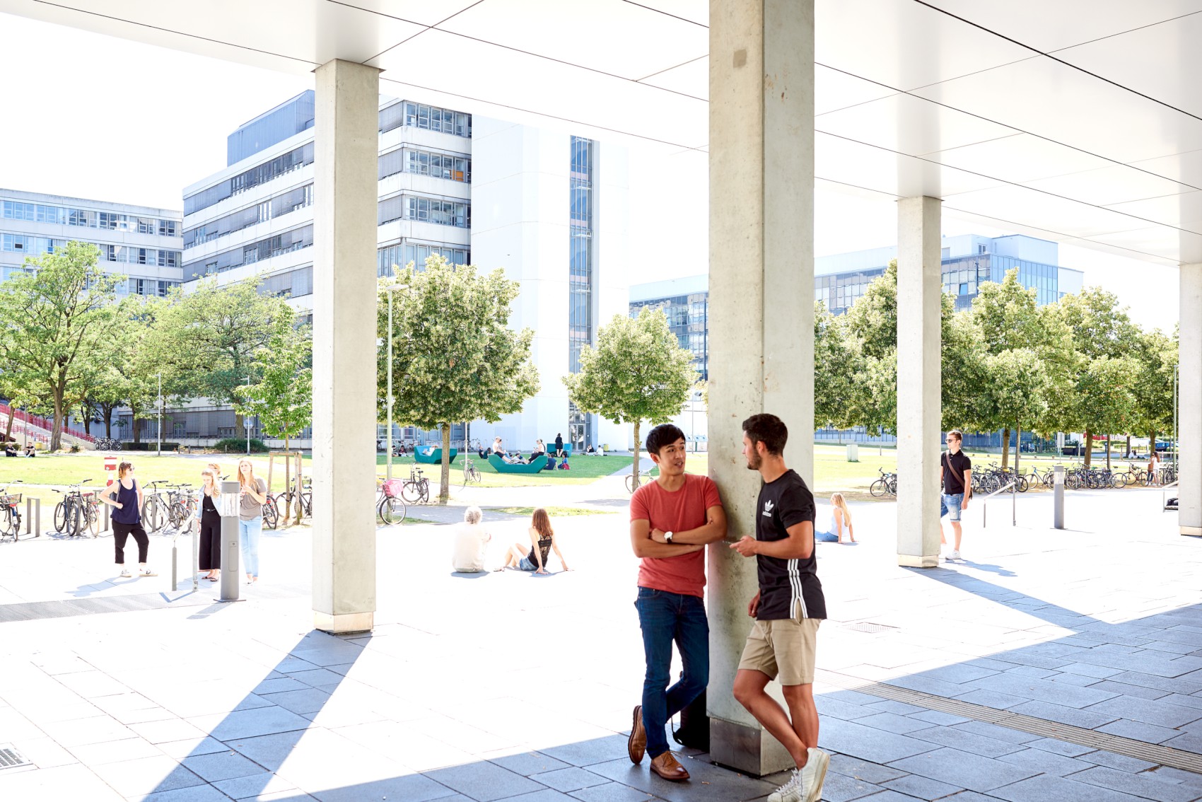 Zwei Studierende stehen auf dem Campus und unterhalten sich